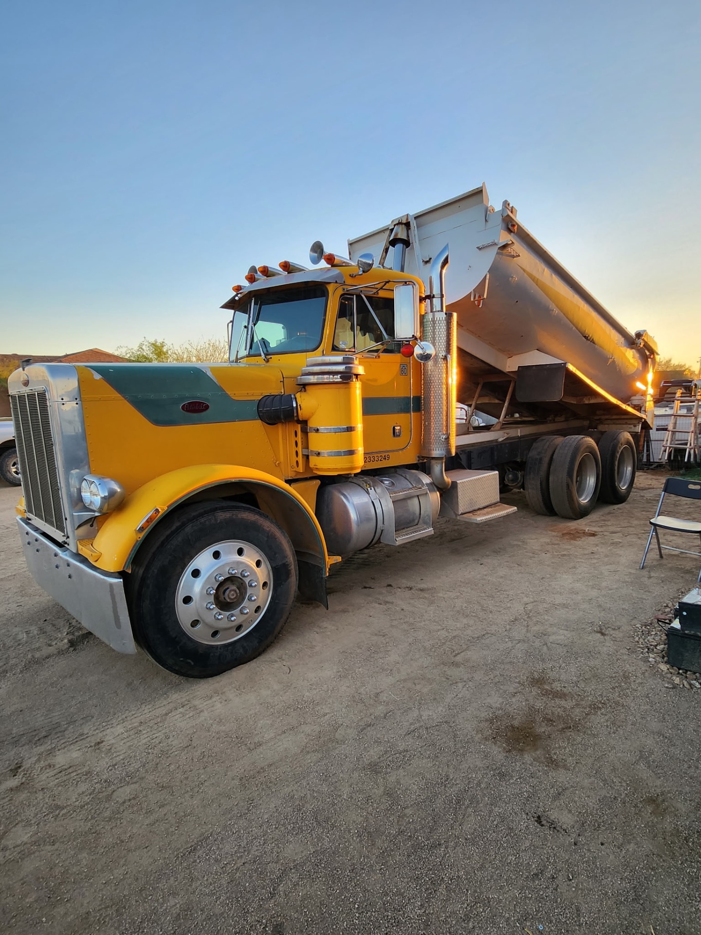 Yellow Peterbilt end-dump truck at dusk
