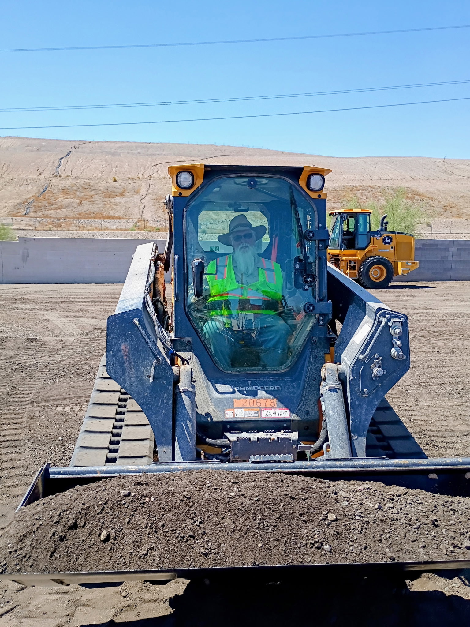 Excavator front-on with a saguaro standing behind