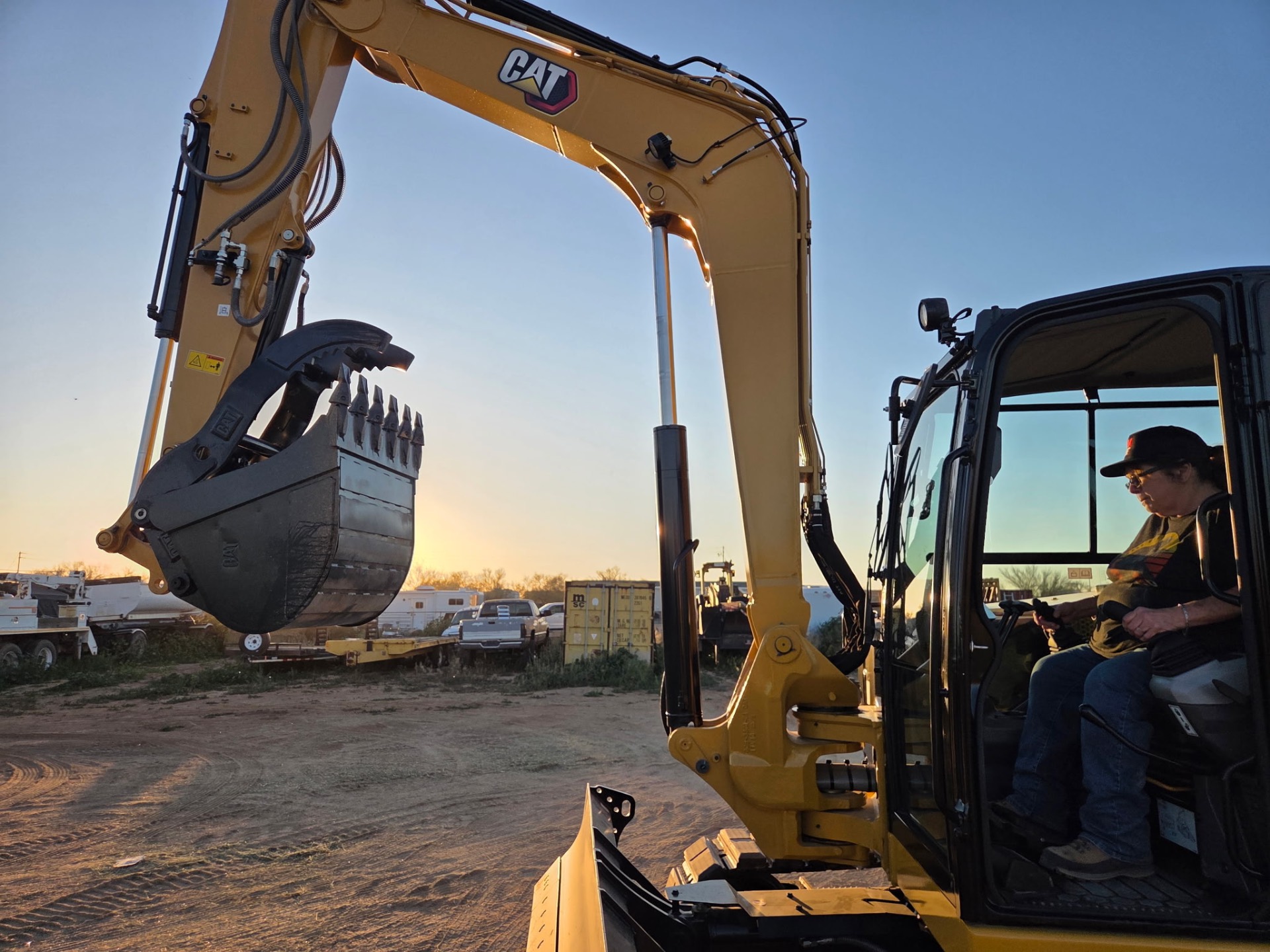 CAT mini-excavator with rock bucket at sunset