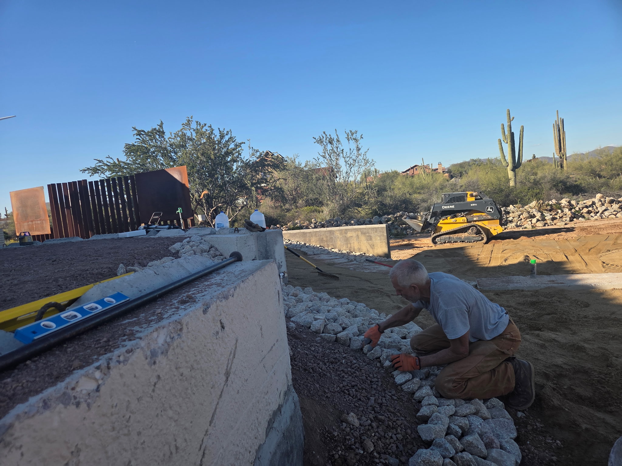 Excavator working a residential cut among saguaros