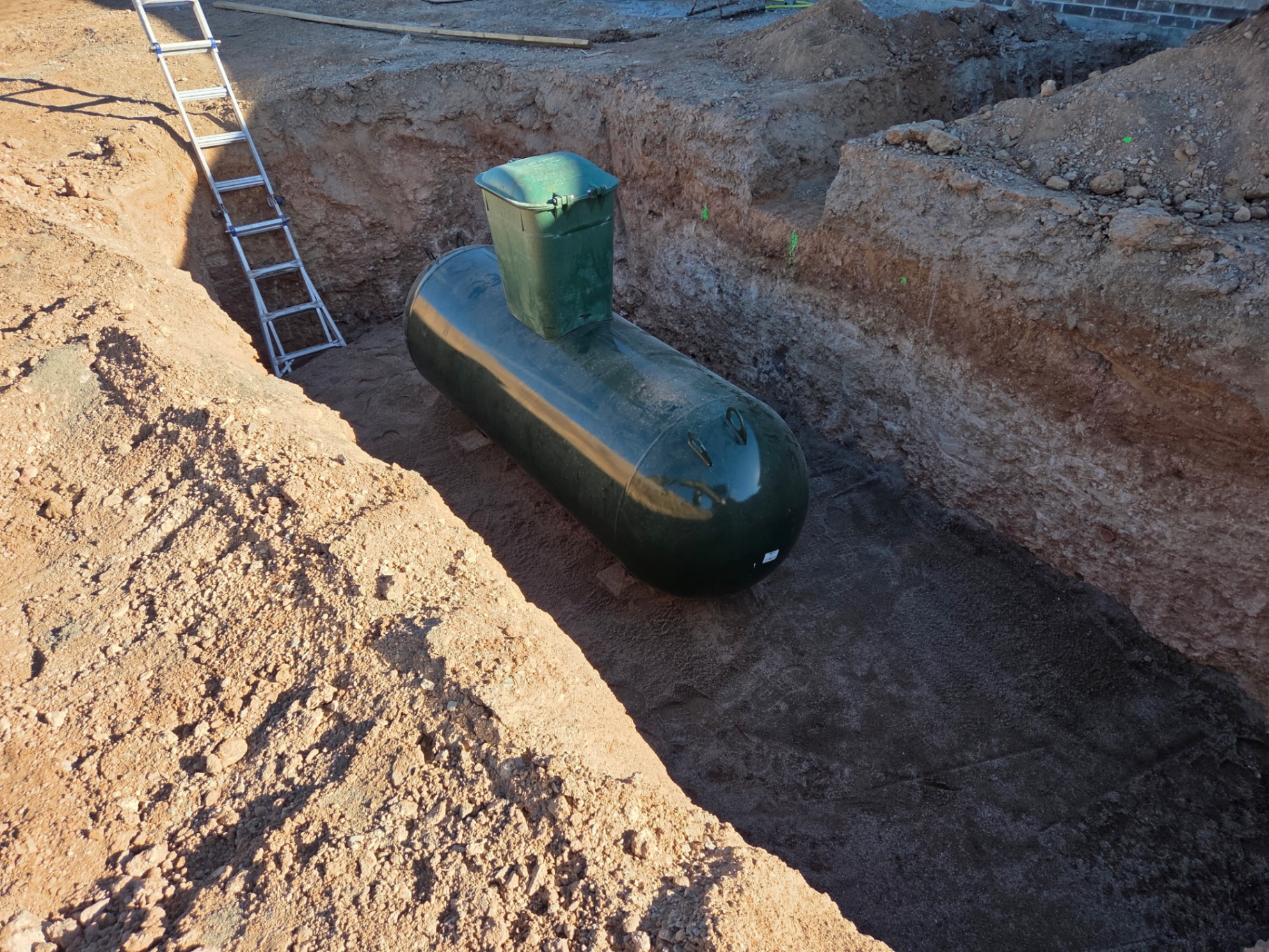 Buried propane tank set in a rock-cut trench on a new build
