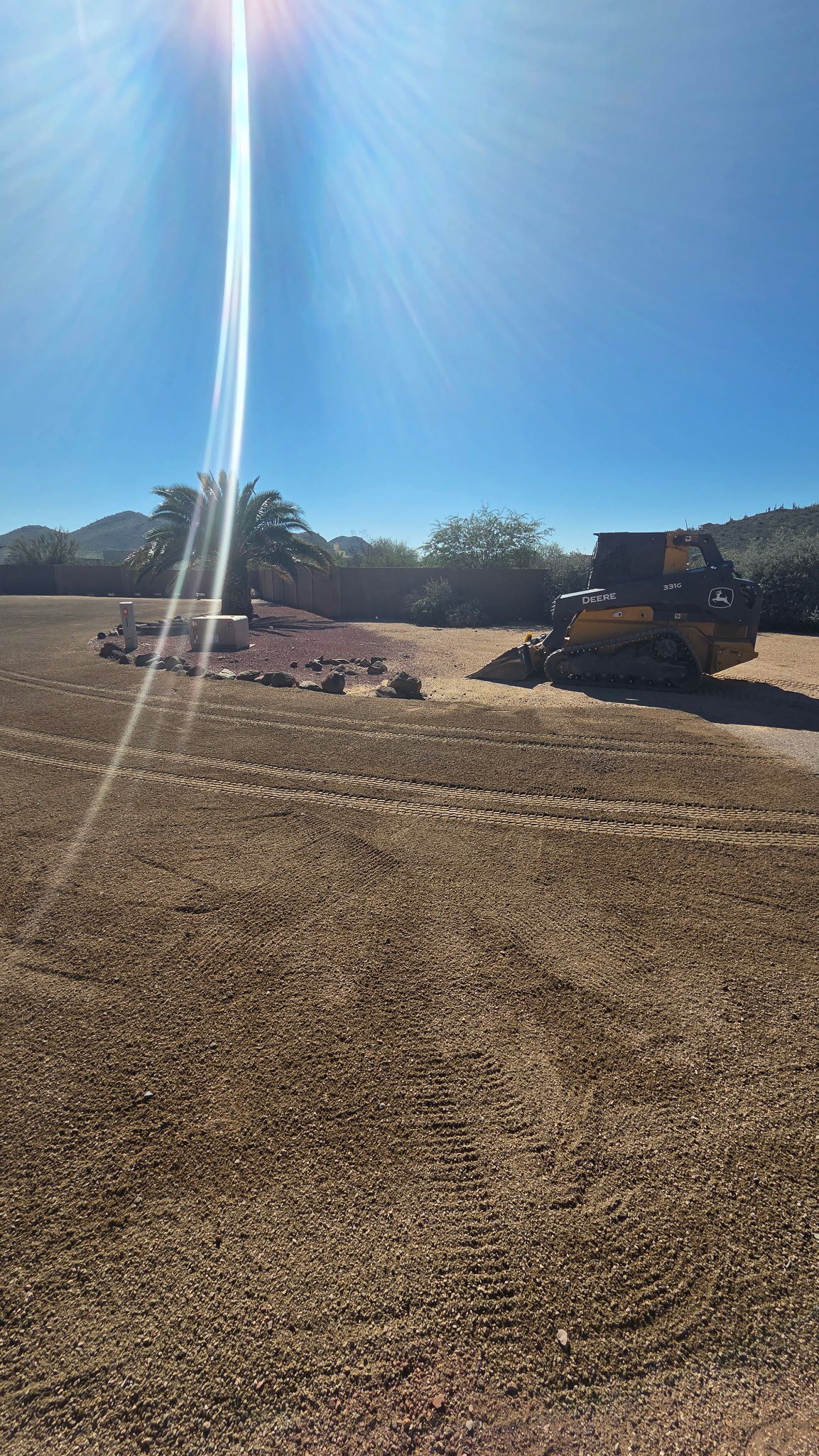 Dozer working a wide-open pad, sun flare across the frame