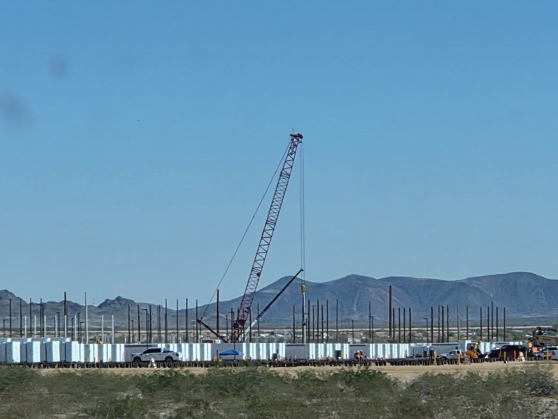 Crane setting battery containers on a utility-scale solar jobsite