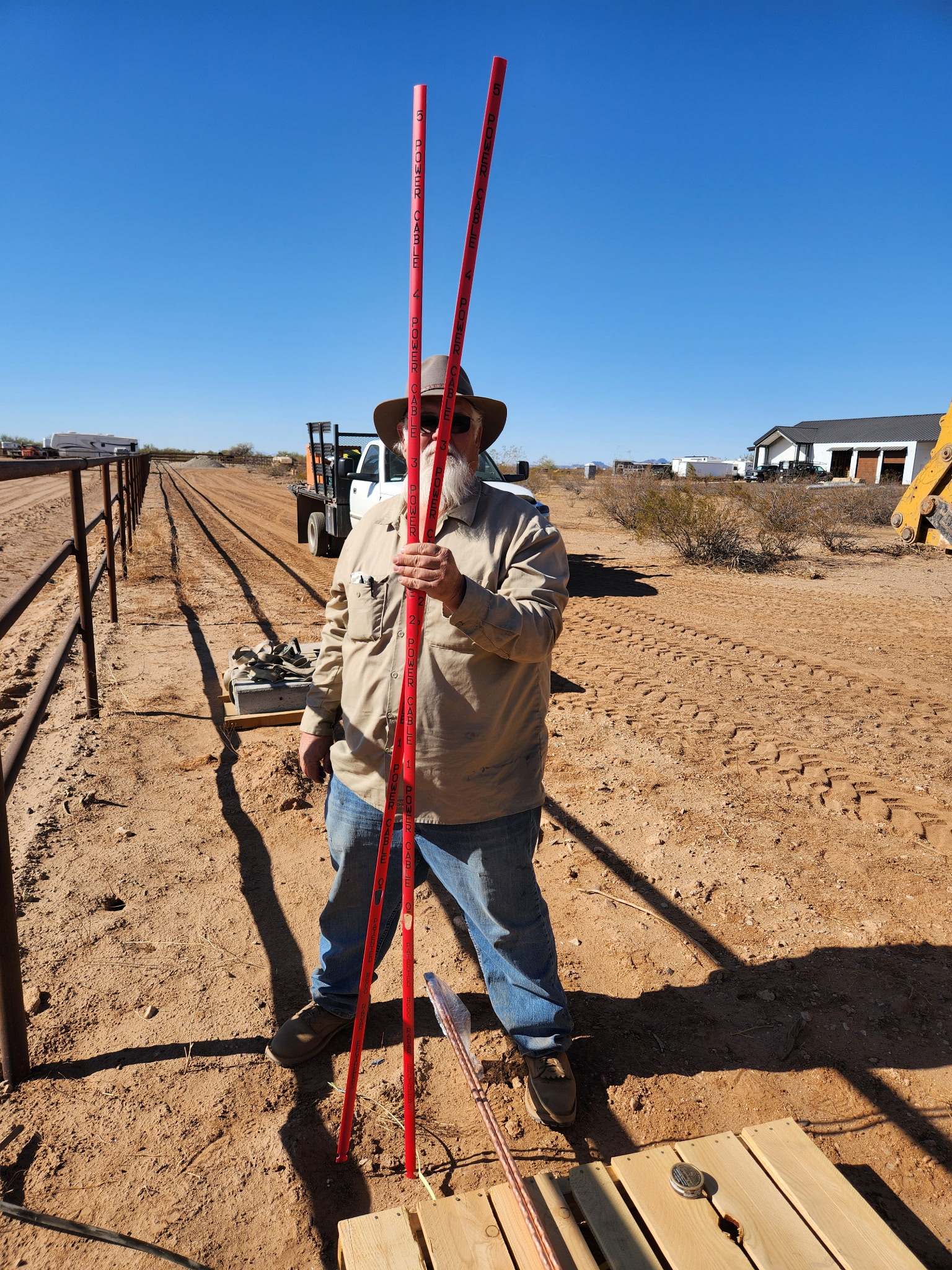 Crew laying grade with survey rods along a wall foundation