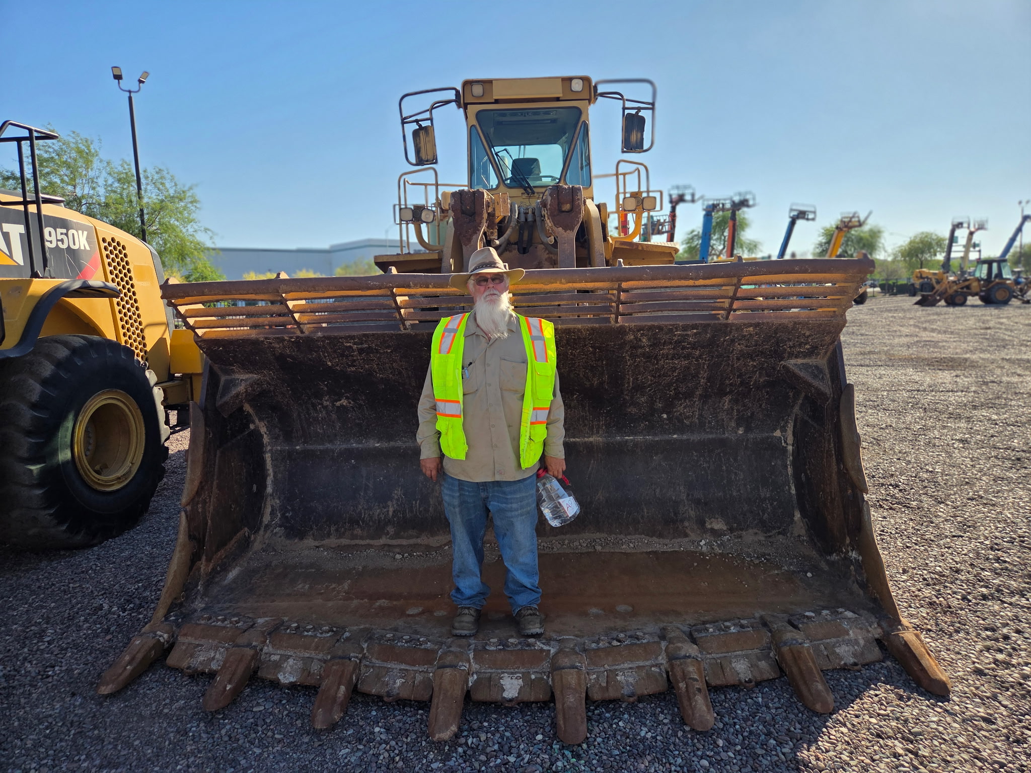 Crew standing in front of the CAT loader bucket