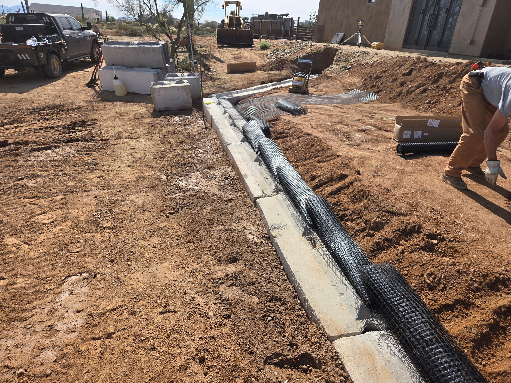 Crew running a utility trench next to a stucco wall