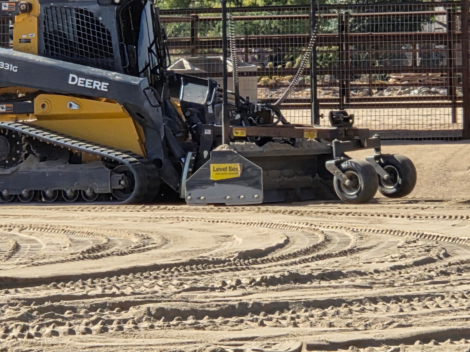 Deere 331G with Level Best grading attachment finishing an arena floor