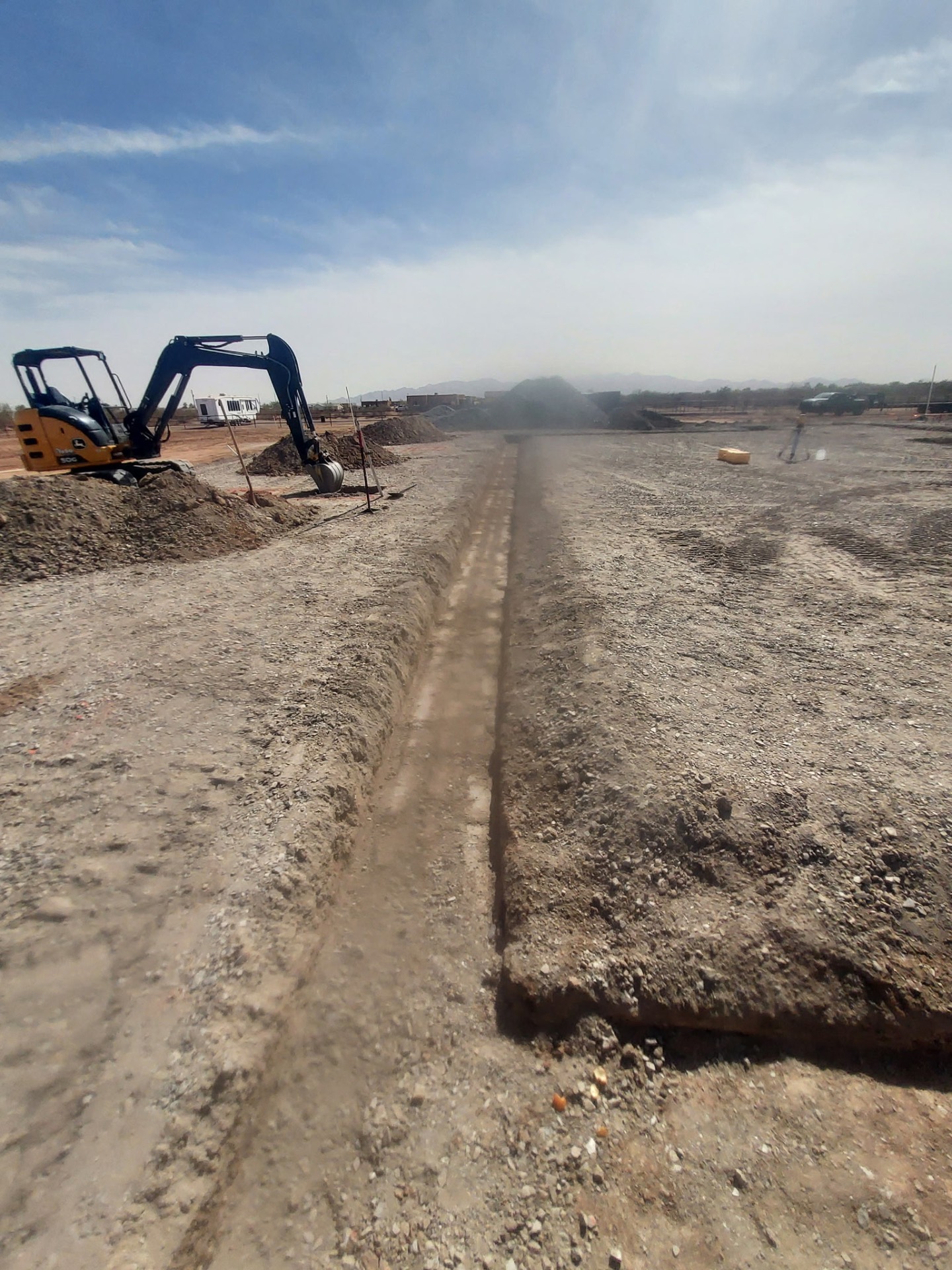 Trench excavation cut by a Deere mini-excavator on a graded pad