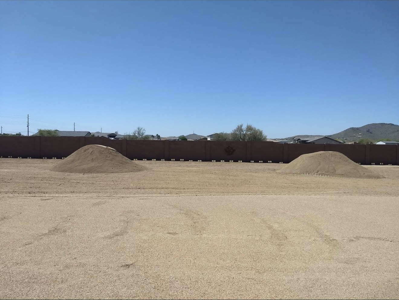 Freshly graded sand arena with two mounds ready to spread