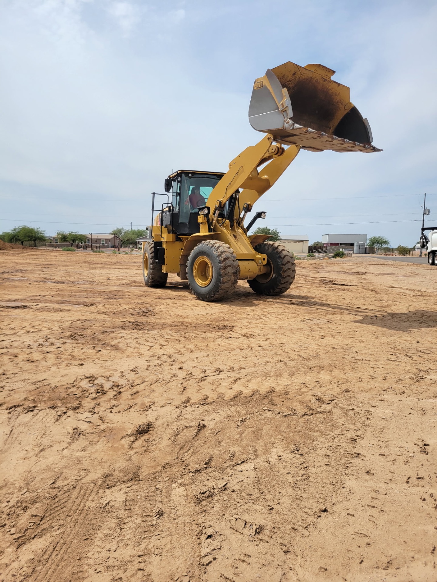 CAT wheel loader bucket raised on a fresh Arizona pad